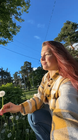 Woman blows dandelions in Vladimir field amid spring afternoon