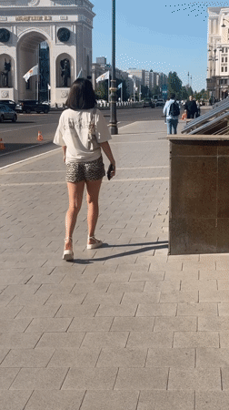 Woman walks city sidewalk in downtown Astana