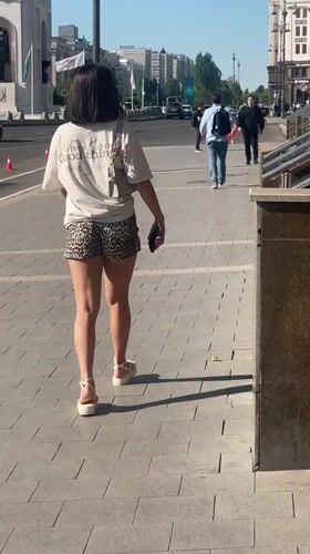 Woman walks city sidewalk in downtown Astana