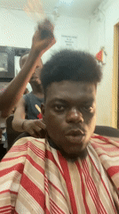Man gets haircut while using smartphone in barbershop