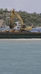 Excavator dumps materials from barge in Nha Trang waters