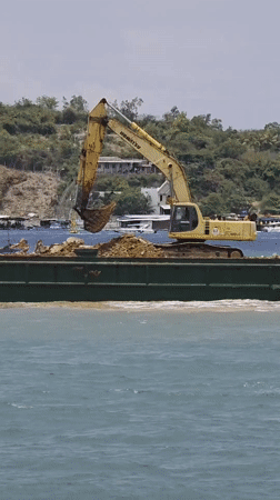 Excavator dumps materials from barge in Nha Trang waters