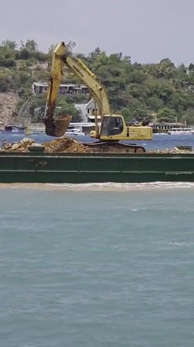 Excavator dumps materials from barge in Nha Trang waters