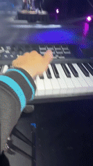 Person operates keyboard controller with keys and drum pads