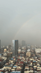 Rainbow over Phnom Penh's dense urban skyline on a hazy morning