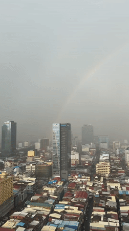Rainbow over Phnom Penh's dense urban skyline on a hazy morning