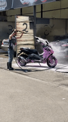 Man pressure washes scooter at Tbilisi car wash