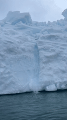 Antarctic iceberg captured with waterfall cascading into ocean waters