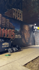 Late-night NYC block: murals, wet streets, and a food truck