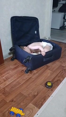 Toddler plays inside suitcase with toys in Ufa home