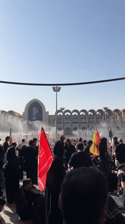 Large crowd with flags assembles outdoors in Tehran