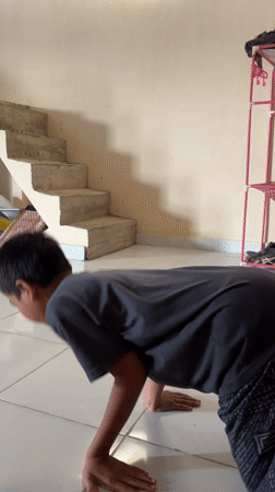 Boy practices breakdancing moves indoors while cat watches