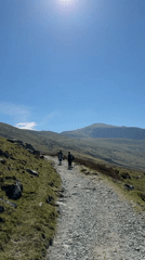 Hikers traverse mountain path in Llanberis under clear skies