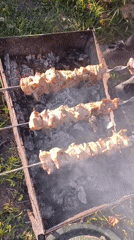 Elderly man grills meat, drinks beer in Botovo backyard
