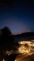 Gorontalo's lit-up waterfront at night, restaurants and palms.
