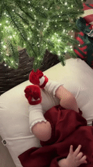 Baby in red outfit photographed under Christmas tree in St. Petersburg