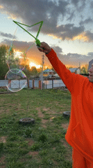 Couple blows soap bubbles at sunset in Chaikovsky yard