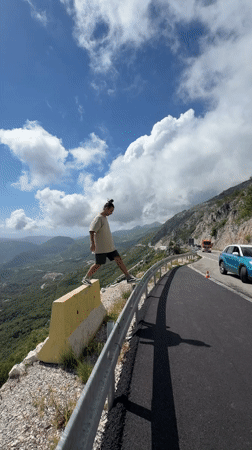 Man poses on highway guardrail in Montenegro mountains
