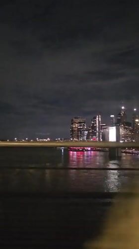 Blurry nighttime NYC skyline reflected across the water