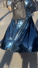 Person in shiny raincoat walks London sidewalk