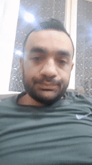 Bearded man in green shirt photographed indoors near window