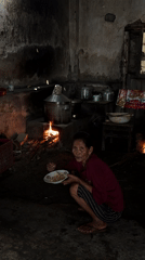 Women gather while elderly resident dines in Kebonsari village