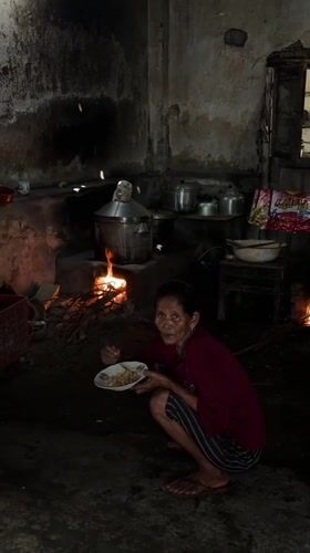 Women gather while elderly resident dines in Kebonsari village