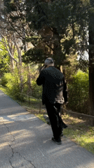 Elderly person in black walks paved path in Pržno