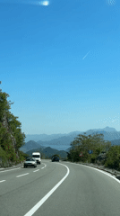 Driver records scenic mountain road with distant lake view