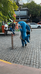 Shark-costumed person walks toward colorful Dino Train bus in Buenos Aires