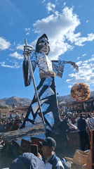Skeletal effigy and Cusco helicopter at an outdoor ceremonial event