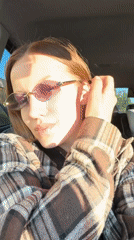 Woman adjusts sunglasses while sitting in car in Klin