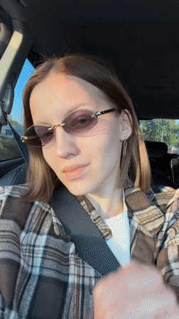 Woman adjusts sunglasses while sitting in car in Klin