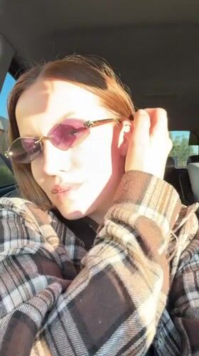 Woman adjusts sunglasses while sitting in car in Klin
