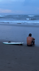 Man sits on beach sand in North Kuta Indonesia