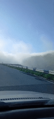 Vehicle drives mountain road in foggy conditions early morning