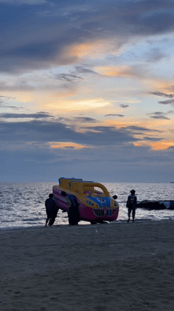 Sunset activity on Pattaya Beach: excavator, jet skis, and an inflatable car