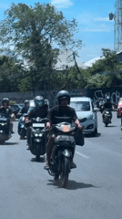 Motorcycle procession travels through Kuta streets on sunny day