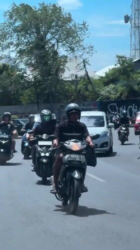 Motorcycle procession travels through Kuta streets on sunny day