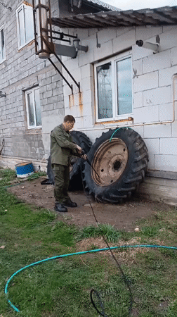 Man performs vehicle maintenance in Andreyevo yard with pets