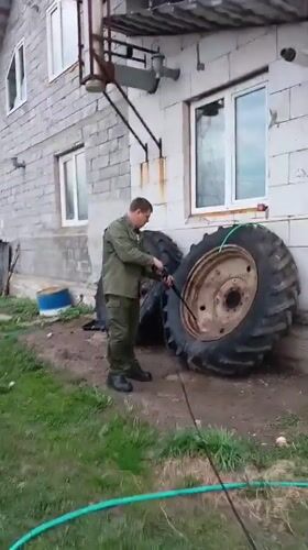 Man performs vehicle maintenance in Andreyevo yard with pets