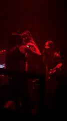 Three women perform music in red-lit Milan venue