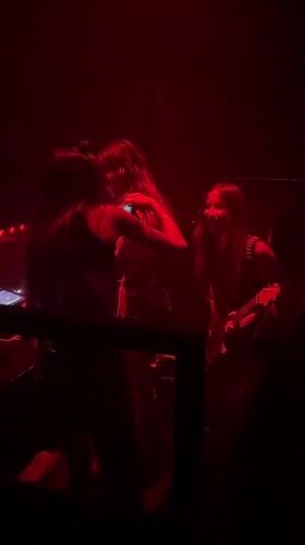 Three women perform music in red-lit Milan venue