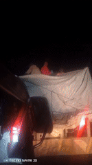 People ride in truck bed under tarp during night