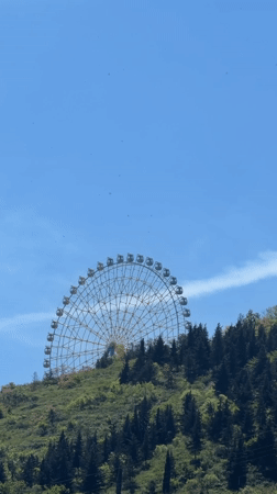 Ferris wheel spotted on hilltop in Tbilisi under clear skies