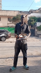Holding a pot and performing on a Nairobi sidewalk