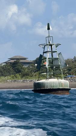 Green navigation buoy rides the waves off Bali's coast