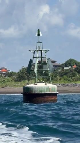 Green navigation buoy rides the waves off Bali's coast
