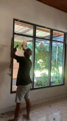 Chiseling plaster from a window frame in Sukasada
