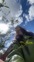 Woman observes spring blossoms under cloudy sky in Foki